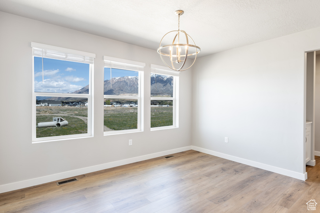 Unfurnished room featuring baseboards, a chandelier, visible vents, and light wood-type flooring