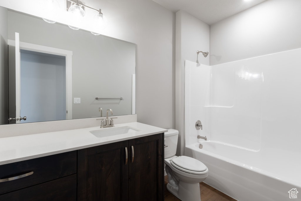 Bathroom featuring wood finished floors, toilet, vanity, and shower / tub combination