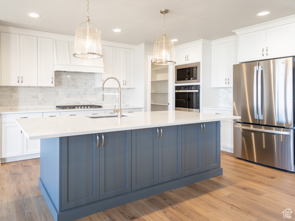 Kitchen featuring tasteful backsplash, a sink, white cabinetry, light countertops, and appliances with stainless steel finishes