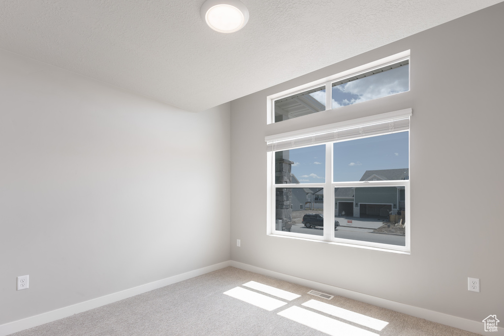 Carpeted spare room with visible vents and baseboards