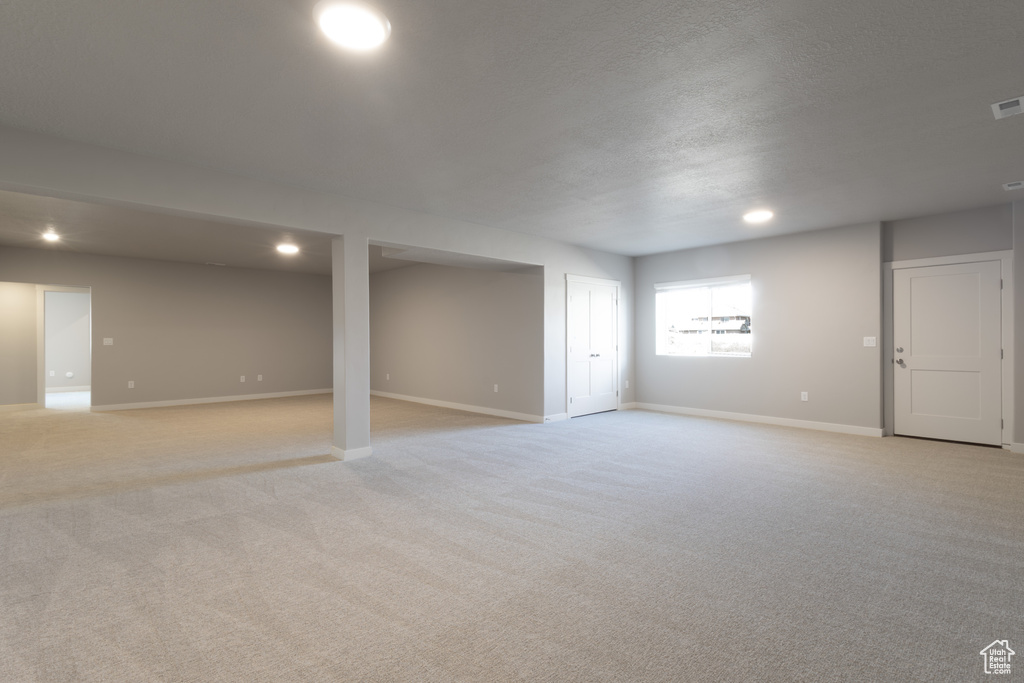 Below grade area featuring visible vents, baseboards, recessed lighting, and light colored carpet