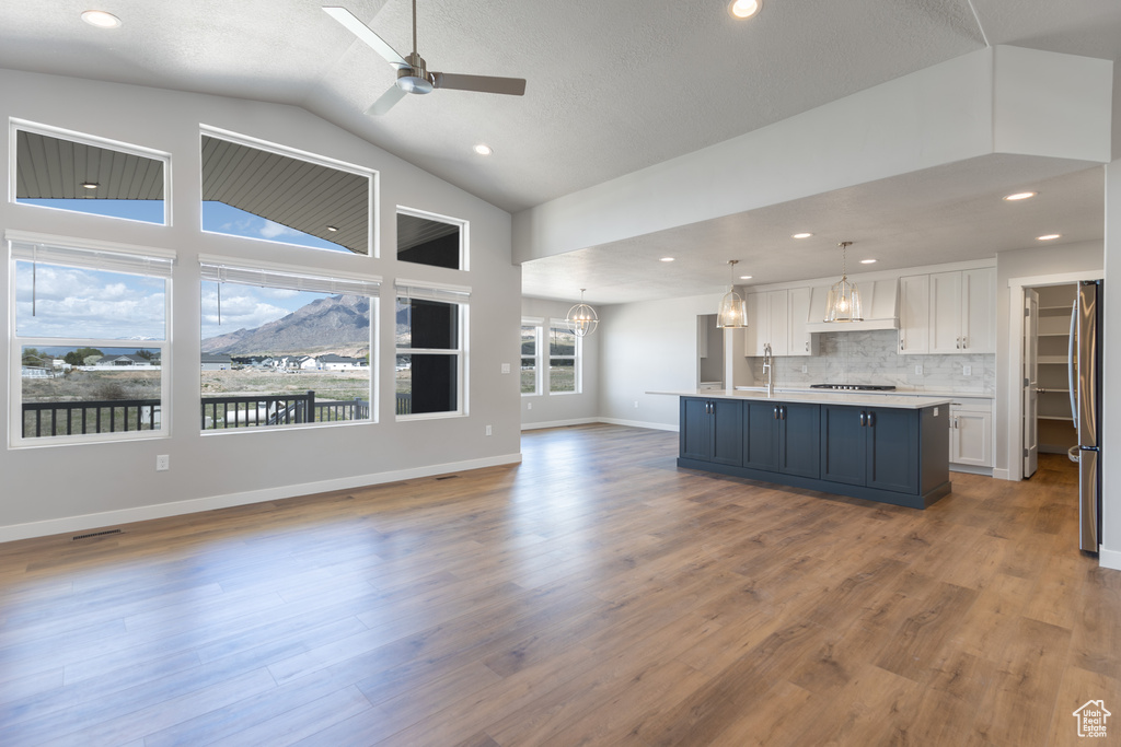 Kitchen with white cabinets, light countertops, premium range hood, freestanding refrigerator, and open floor plan