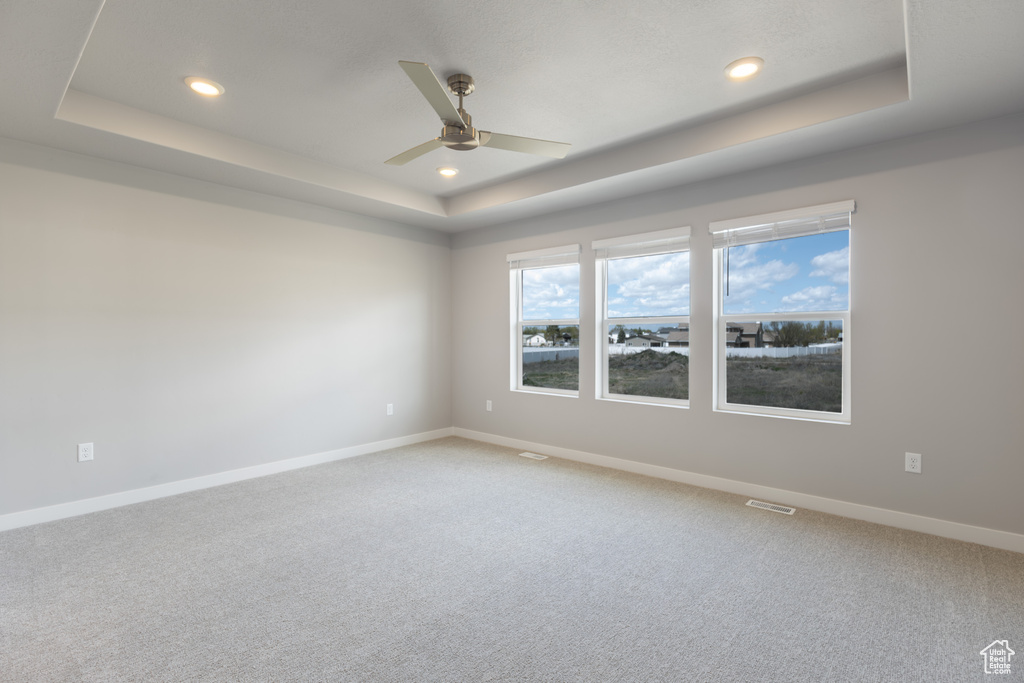 Empty room with ceiling fan, light carpet, a raised ceiling, baseboards, and recessed lighting