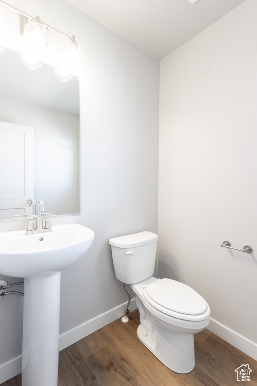 Bathroom with a sink, toilet, wood finished floors, and baseboards