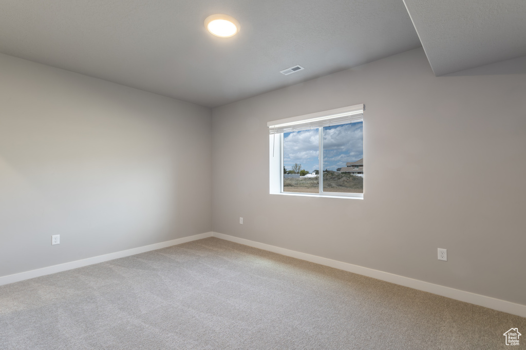 Carpeted spare room featuring baseboards and visible vents