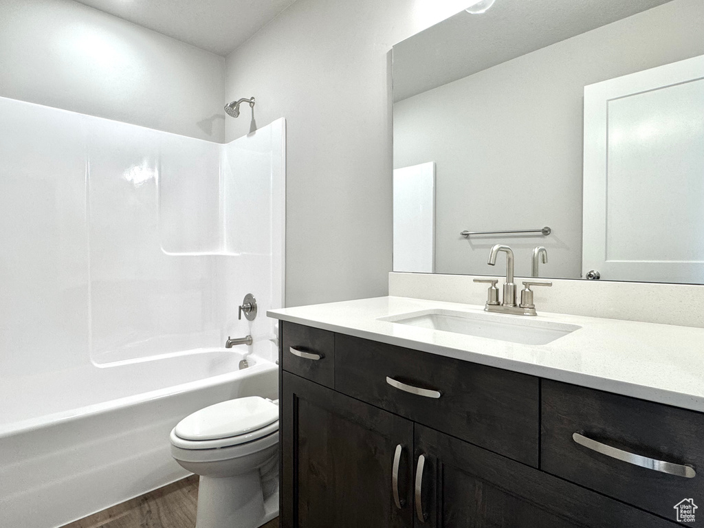 Full bath featuring shower / bathtub combination, wood finished floors, vanity, and toilet