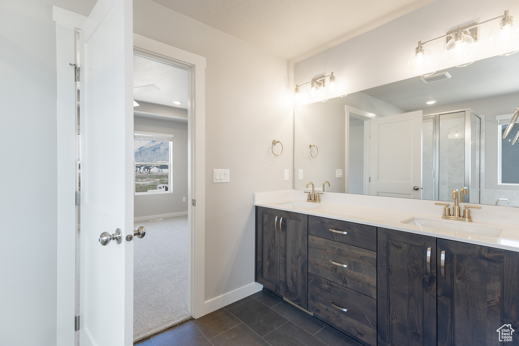 Full bath featuring a sink, a stall shower, double vanity, tile patterned flooring, and visible vents
