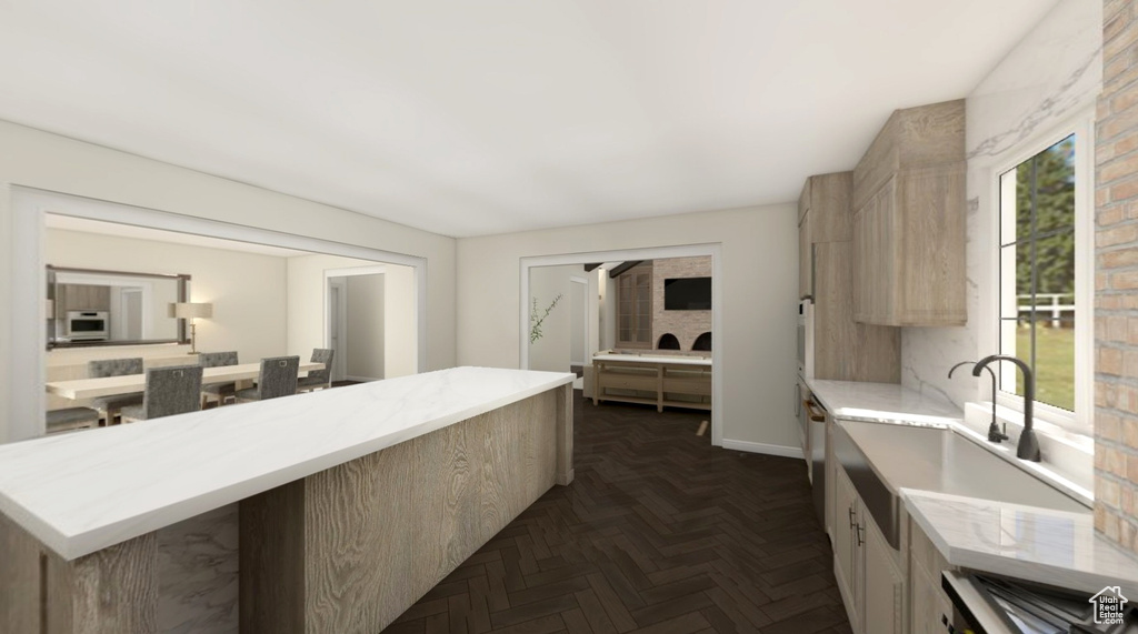 Kitchen featuring a sink, light brown cabinets, white microwave, and light stone counters