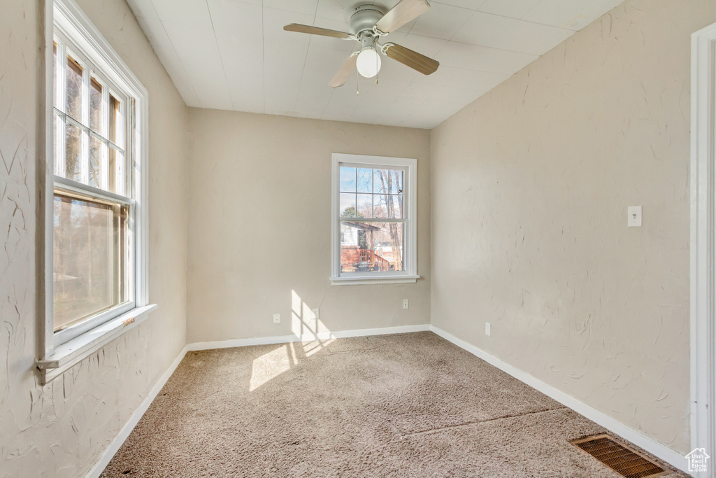 Empty room with baseboards, visible vents, ceiling fan, and carpet