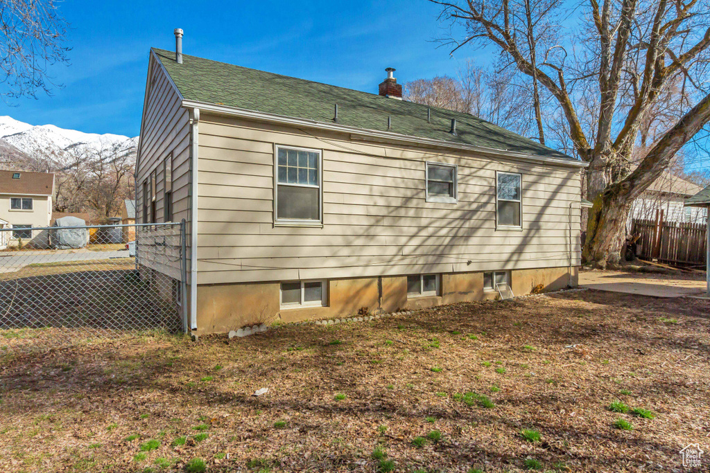Rear view of house featuring fence, a chimney, and a mountain view