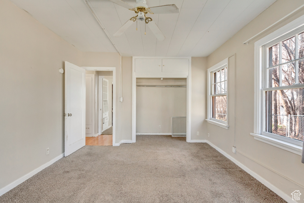 Unfurnished bedroom with a closet, light carpet, and baseboards