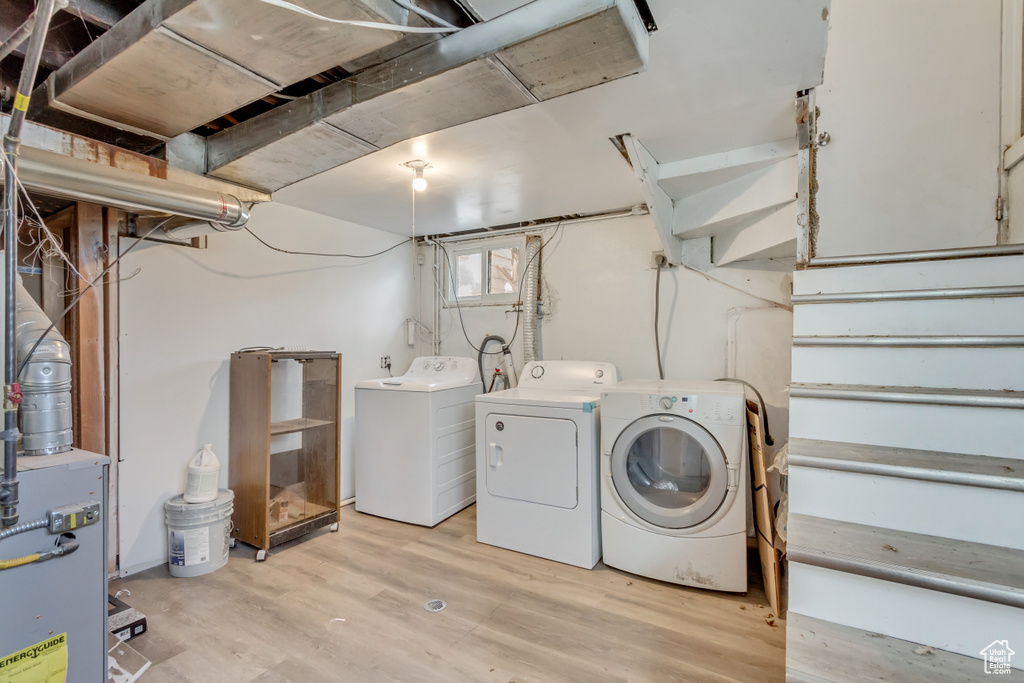 Washroom with independent washer and dryer, light wood-type flooring, and laundry area