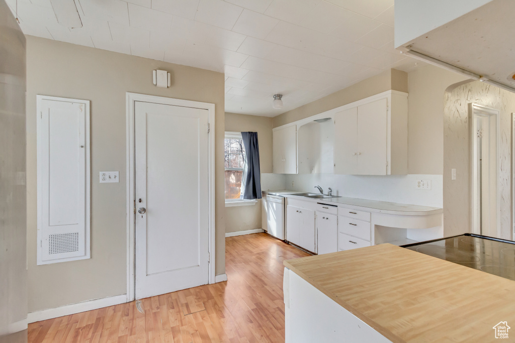 Kitchen with white cabinets, light wood finished floors, light countertops, and a sink