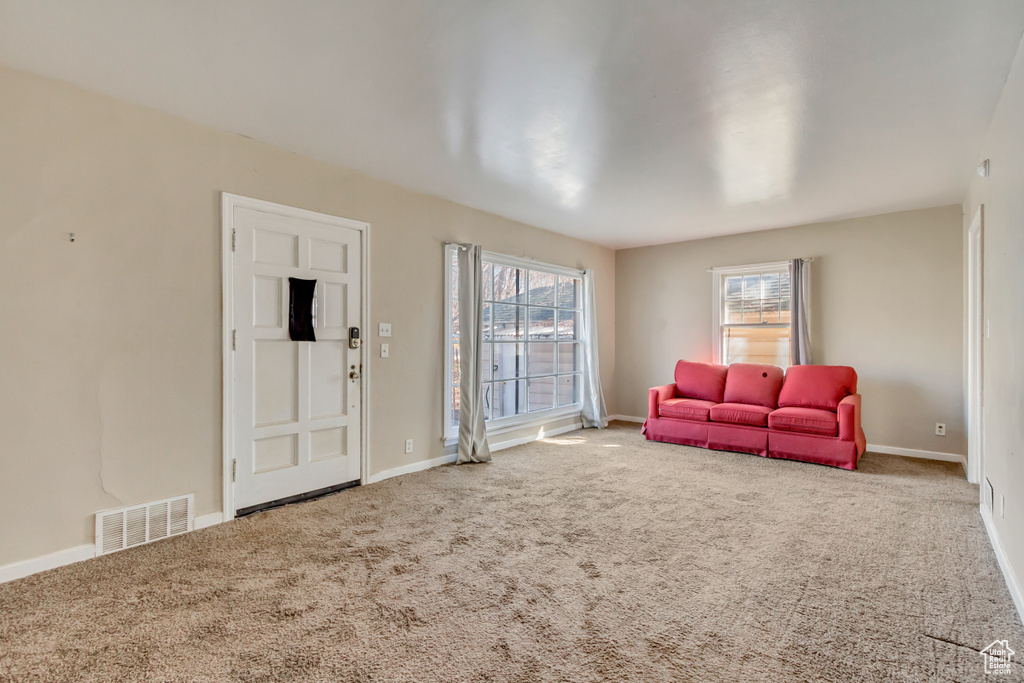 Carpeted living room with visible vents and baseboards