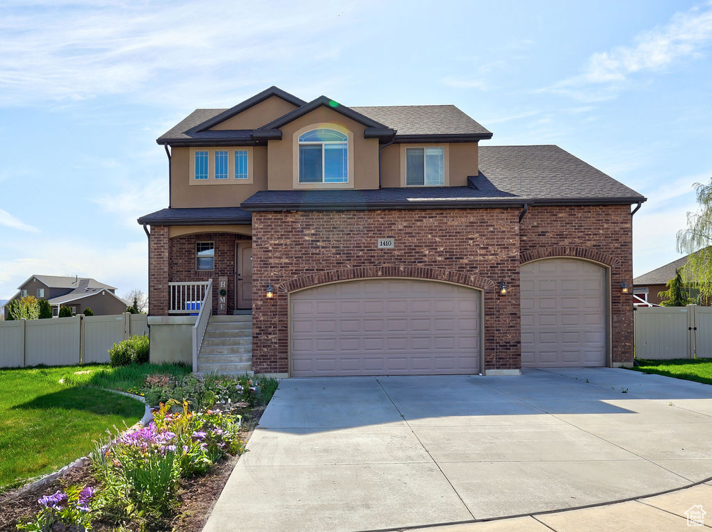 View of front of home featuring stucco siding, fence, driveway, a front yard, and an attached garage