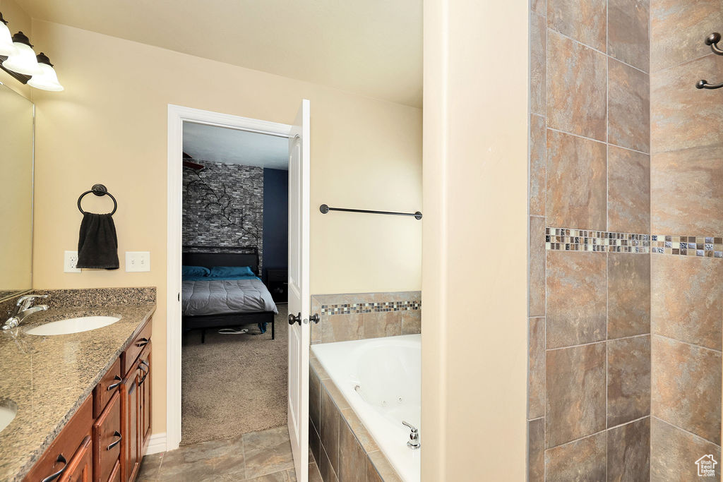 Full bath featuring a whirlpool tub, double vanity, connected bathroom, and a sink