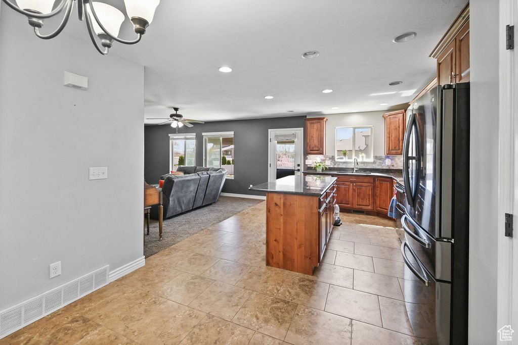 Kitchen featuring a center island, brown cabinets, open floor plan, visible vents, and freestanding refrigerator