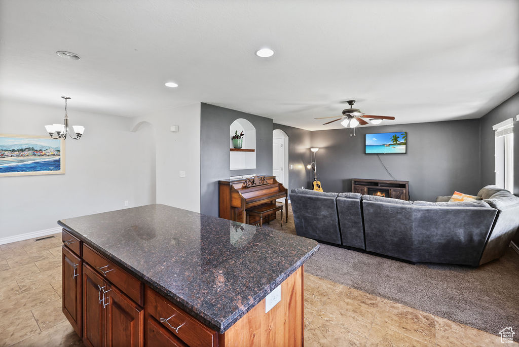 Living area with recessed lighting, arched walkways, a glass covered fireplace, and ceiling fan with notable chandelier