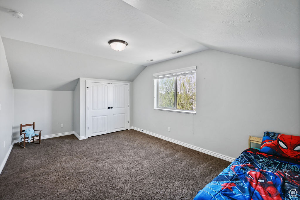 Bonus room with baseboards, vaulted ceiling, visible vents, and dark colored carpet