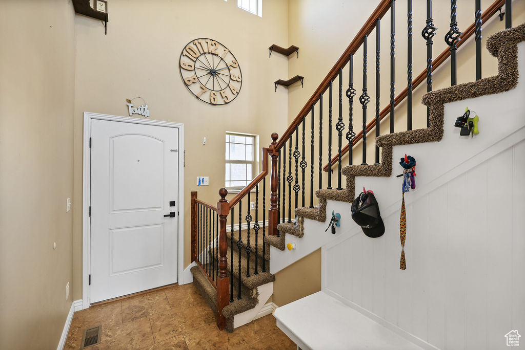 Foyer with a high ceiling, baseboards, stairs, and visible vents