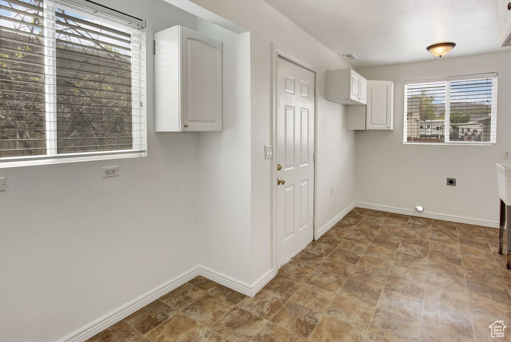 Laundry area featuring baseboards, stone finish flooring, cabinet space, and hookup for an electric dryer