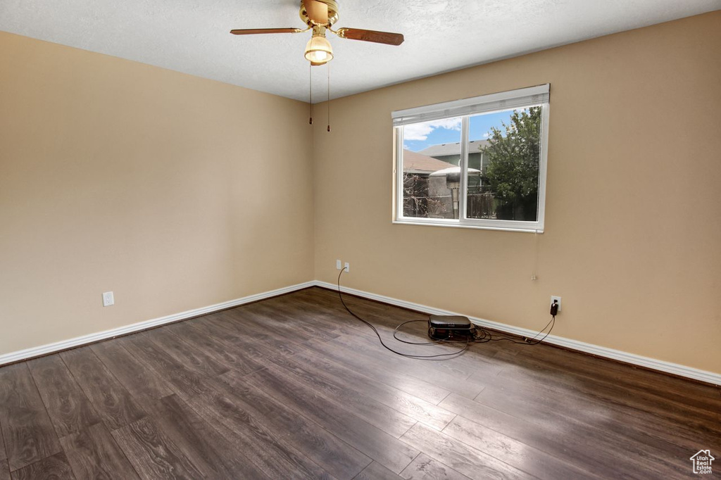 Unfurnished room with a textured ceiling, wood finished floors, a ceiling fan, and baseboards