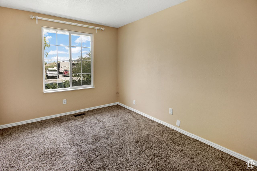 Unfurnished room with baseboards, visible vents, and carpet