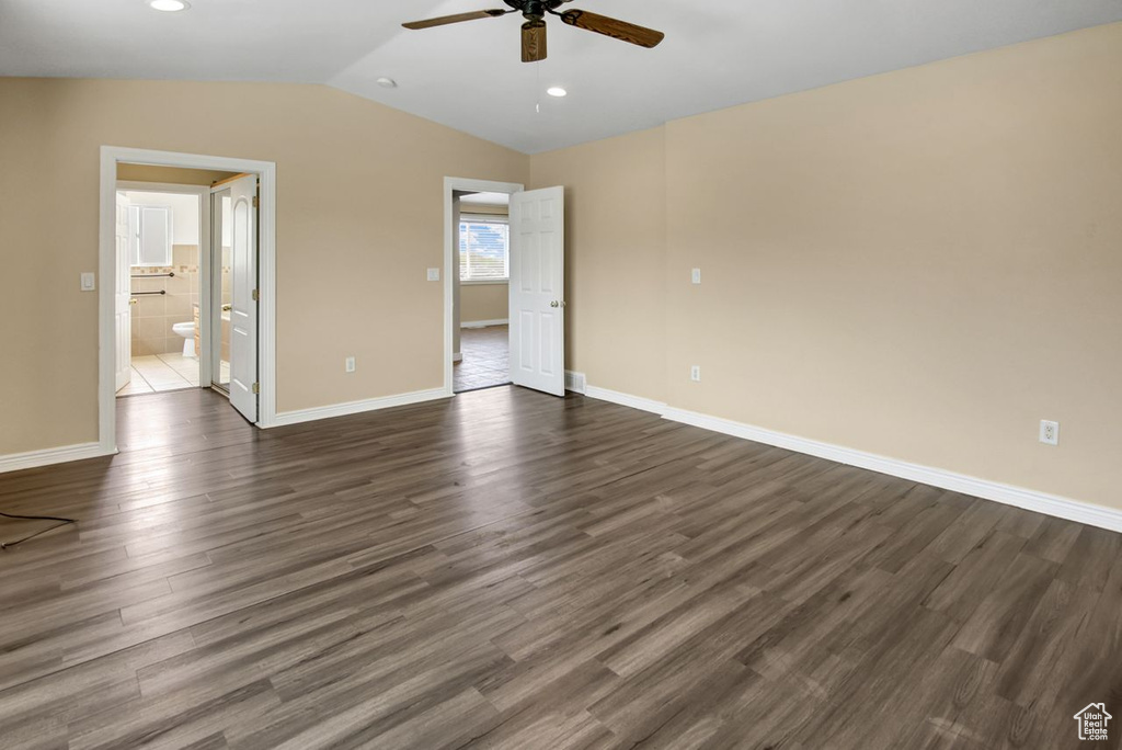 Unfurnished bedroom with baseboards, dark wood-style flooring, and lofted ceiling