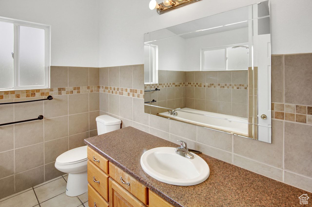 Bathroom with tile walls, toilet, tile patterned flooring, and vanity