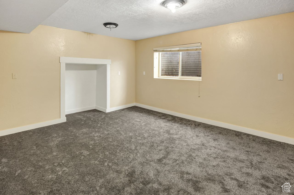 Carpeted empty room featuring baseboards and a textured ceiling