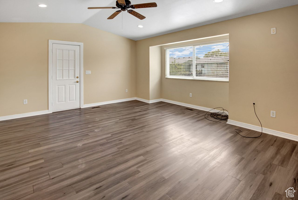 Empty room with dark wood finished floors, baseboards, ceiling fan, and vaulted ceiling
