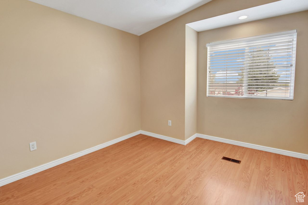Unfurnished room with light wood finished floors, visible vents, and baseboards