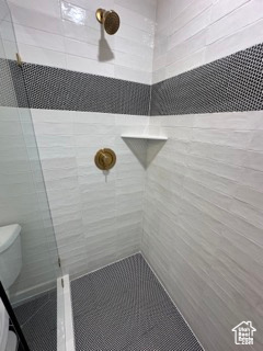 Full bath featuring toilet and a tile shower