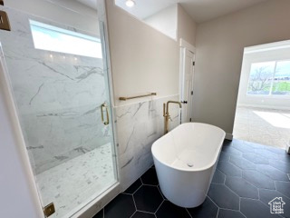 Full bathroom featuring a freestanding tub, a wealth of natural light, tile walls, and a marble finish shower