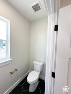Bathroom featuring toilet, tile patterned flooring, visible vents, and baseboards
