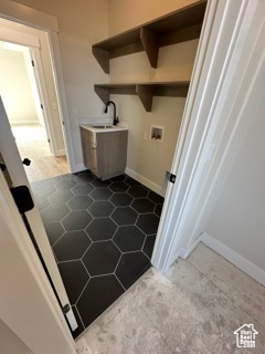 Washroom featuring a sink, laundry area, hookup for a washing machine, baseboards, and dark tile patterned flooring
