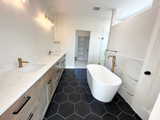 Full bath featuring a soaking tub, a sink, double vanity, visible vents, and walk in shower