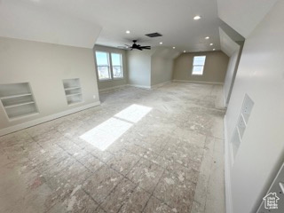 Additional living space with baseboards, recessed lighting, vaulted ceiling, a ceiling fan, and built in shelves