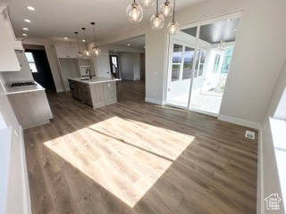 Kitchen with dark wood-type flooring, an inviting chandelier, open floor plan, and baseboards
