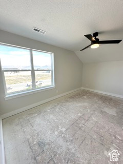 Bonus room with lofted ceiling, a textured ceiling, visible vents, ceiling fan, and baseboards