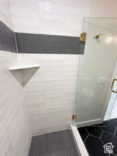 Full bath with tile patterned floors and a shower stall