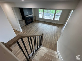 Stairway featuring baseboards, recessed lighting, wood finished floors, and a fireplace