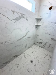 Full bath with a marble finish shower