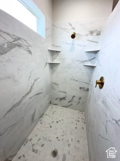 Full bath featuring a marble finish shower