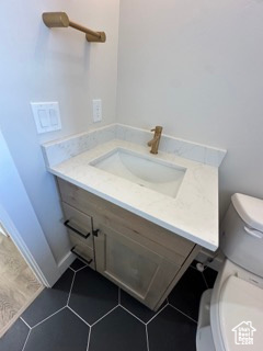 Half bath with tile patterned floors, vanity, and toilet