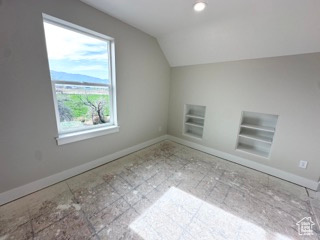 Bonus room featuring built in shelves, vaulted ceiling, and baseboards