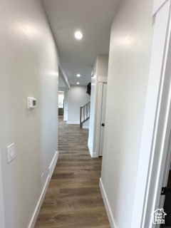 Hallway featuring baseboards, recessed lighting, and dark wood-style flooring