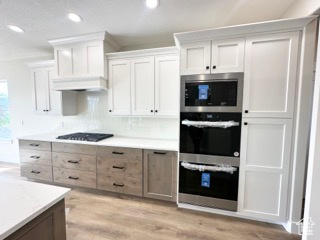 Kitchen featuring recessed lighting, light wood-style flooring, decorative backsplash, appliances with stainless steel finishes, and light countertops