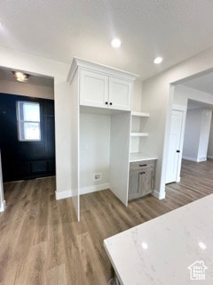 Interior space with wood finished floors, white cabinetry, open shelves, and baseboards