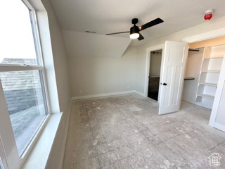 Unfurnished bedroom with ceiling fan, vaulted ceiling, and a spacious closet
